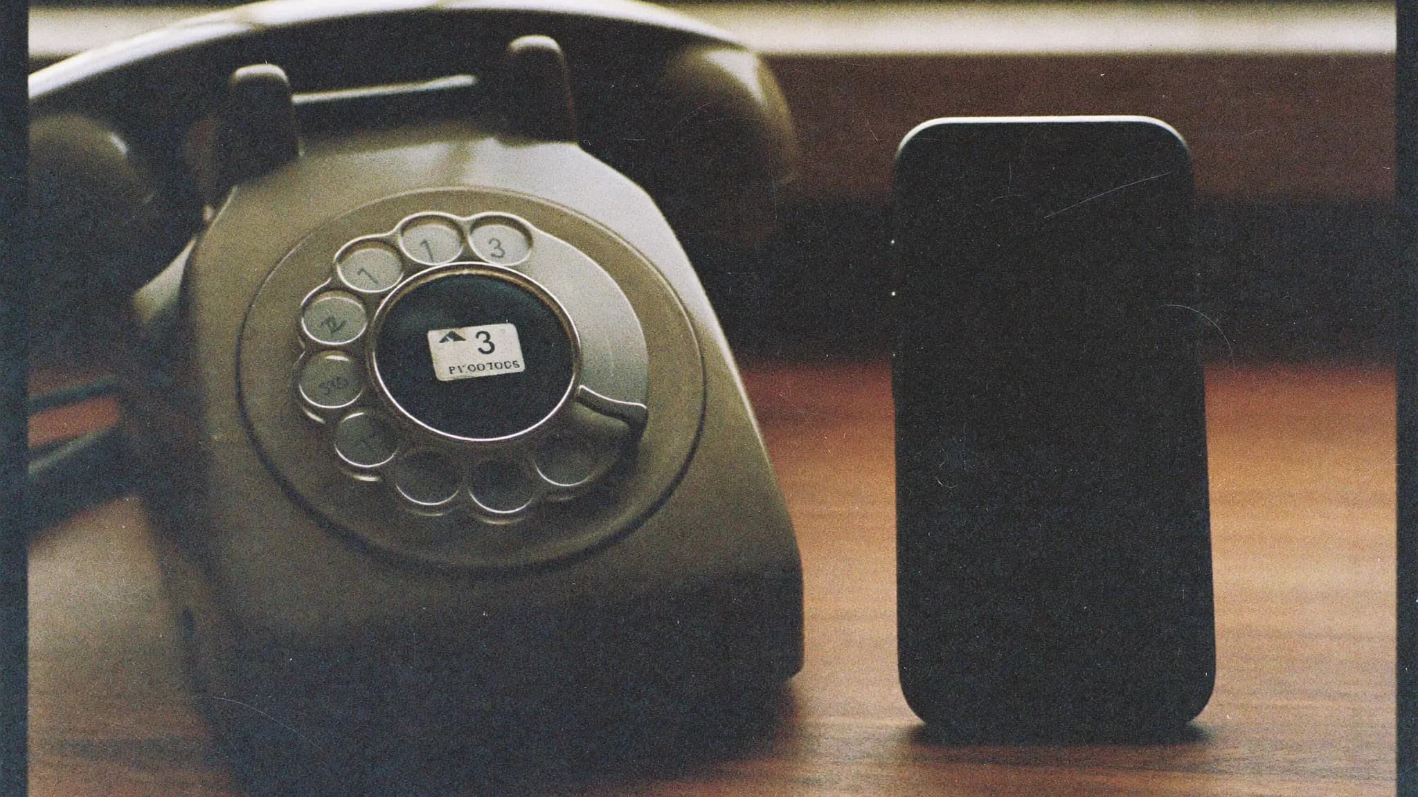 Retro filmfoto av en gammal telefon bredvid en modern mobil – gammalt möter nytt.
