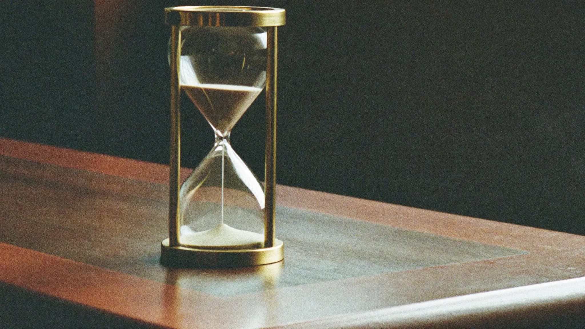 Retro filmfoto av ett timglas på ett skrivbord – hur lång tid en hemsida tar.