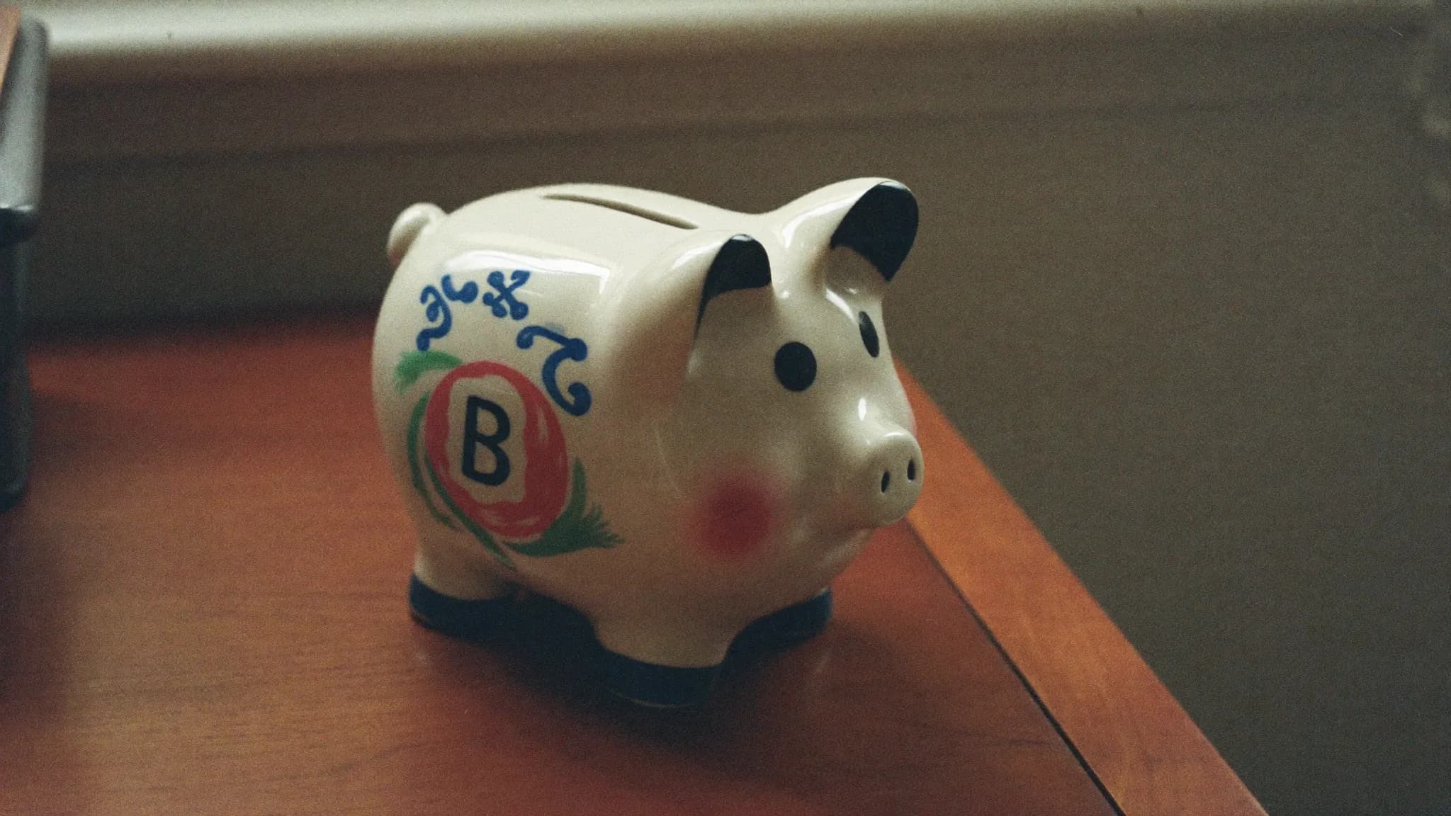 Retro filmfoto av en sparbössa på ett skrivbord – vad en hemsida kostar.