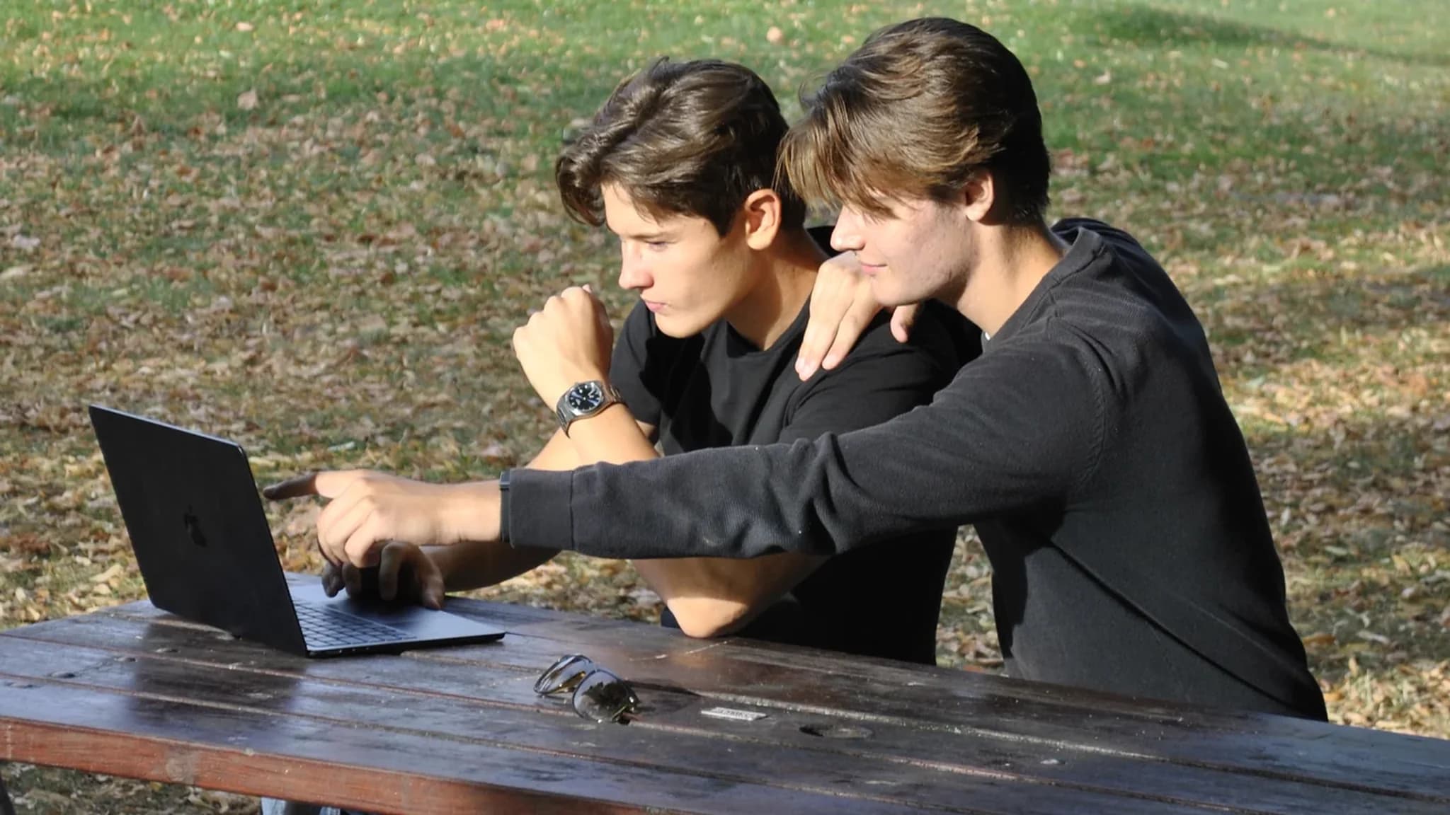 Nod Marketings grundare går igenom en sajt på en laptop vid ett picknickbord i parken.