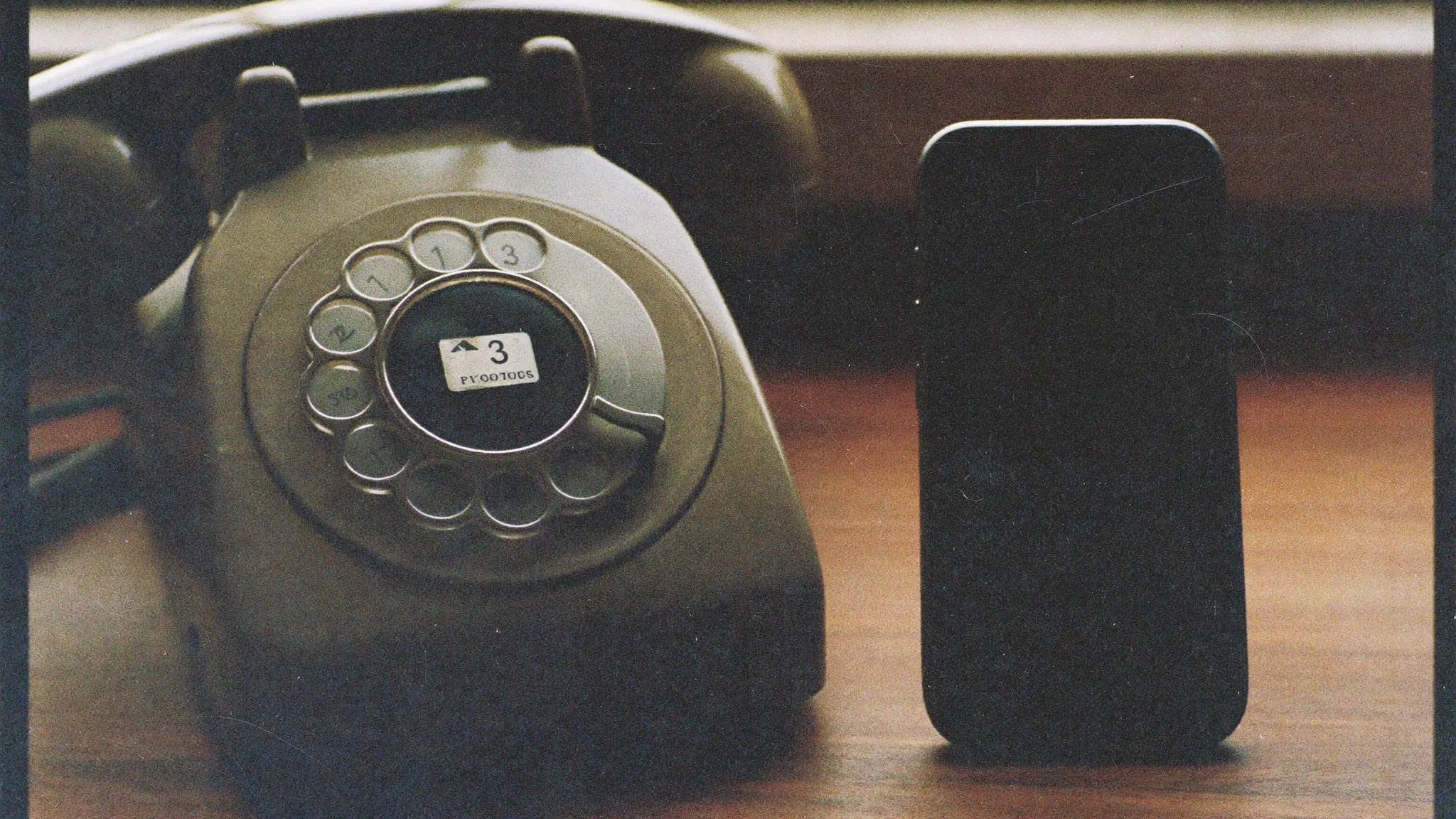 Retro filmfoto av en gammal telefon bredvid en modern mobil – gammalt möter nytt.