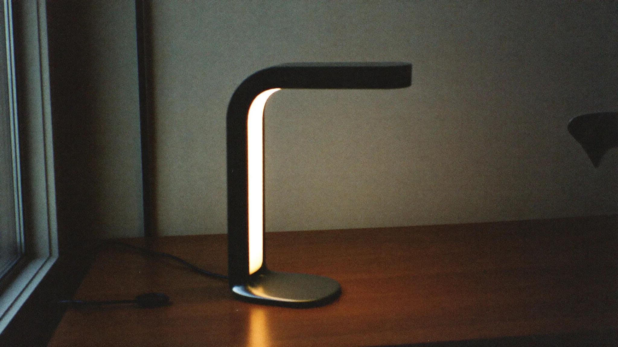 Retro filmfoto av en stilren designlampa som lyser varmt – premium och avancerat.
