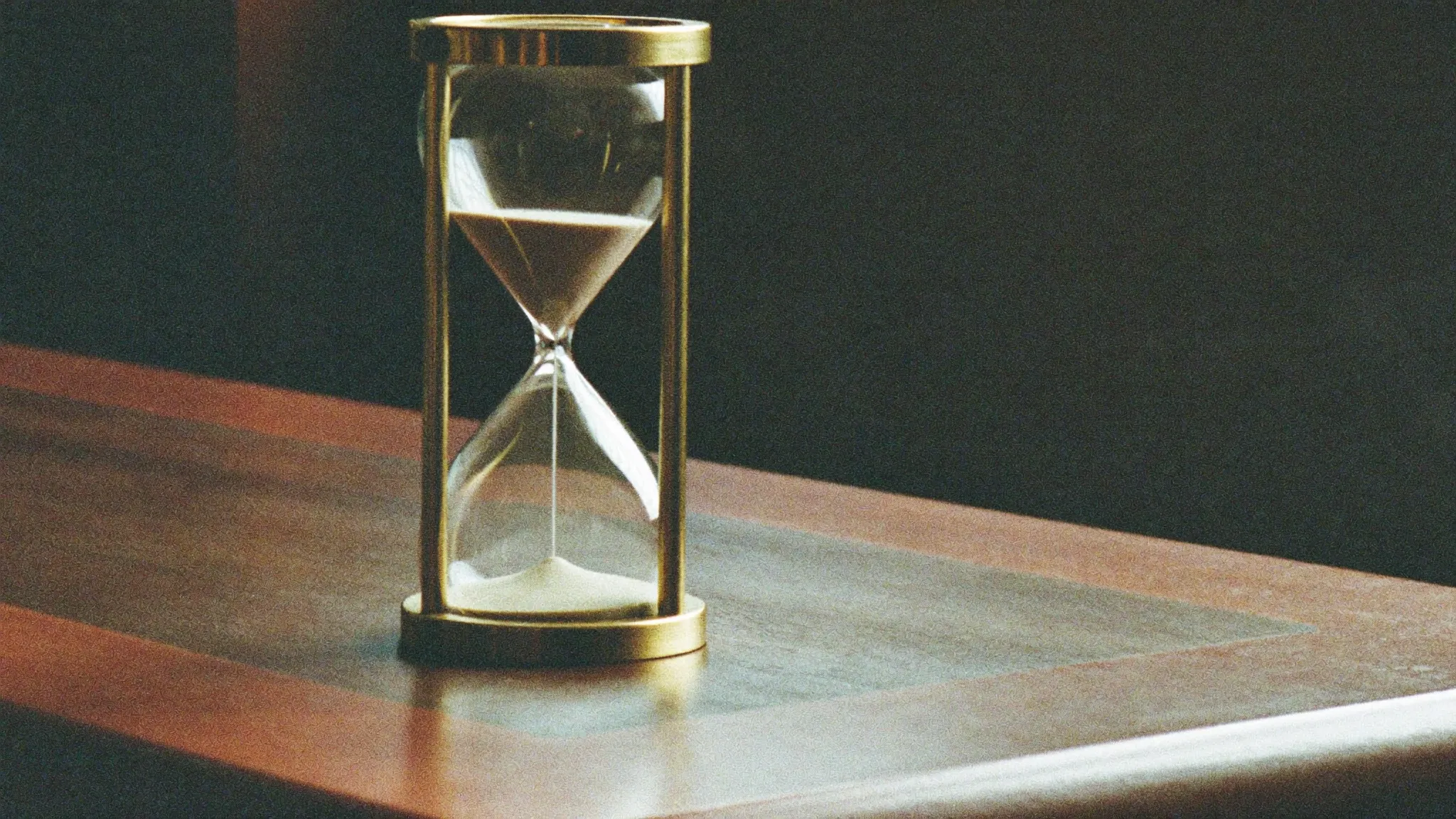 Retro filmfoto av ett timglas på ett skrivbord – hur lång tid en hemsida tar.